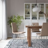Moderne spiseplads: LILLÅNÄS stole omkring træbord, plante, sort-hvidt tæppe, pendel.