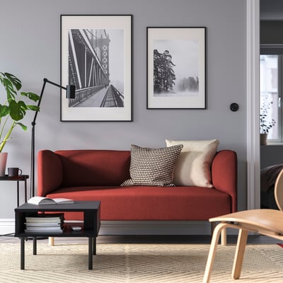 Rød LILLEHEM sofa, hyggelig stue, grøn plante, bøger, krus, moderne kunst.