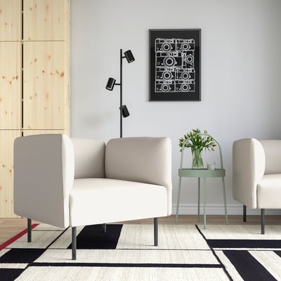 Moderne stue med en hvid LILLEHEM sofa og sideborde. Dekoreret med et geometrisk tæppe, et kunstværk og en grøn skammel med blomster.