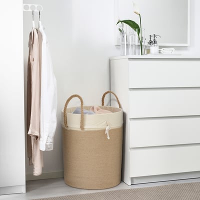 LJUNGAN beige jute vasketøjskurv, stor, med håndtag, nær hvid kommode, der holder tøj.