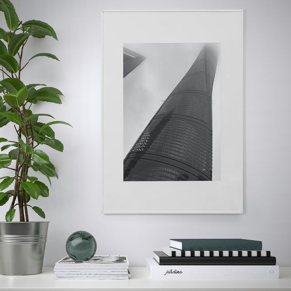 Moderne stue med LOMVIKEN sort/hvid skyskraber fotoramme, metalkant, omgivet af bøger og grønne planter.