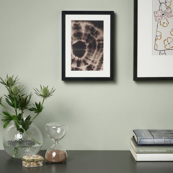 Indrammet kunst, blomster, timeglas, æske, bøger på bordet.