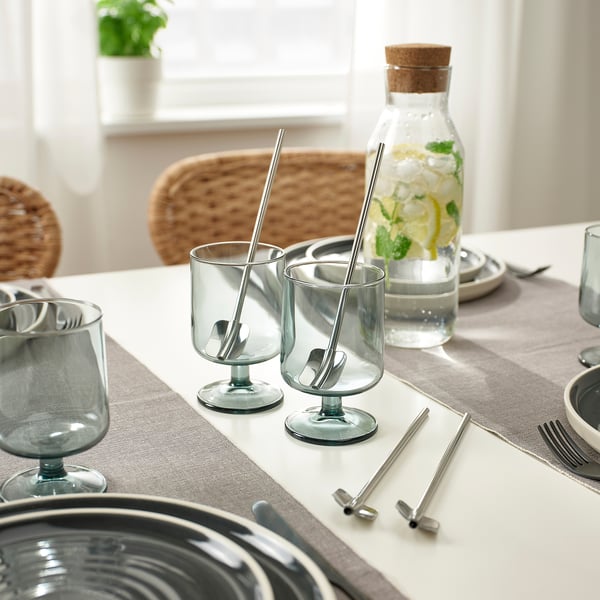 Borddækning med blå glas og metalsugerør med skeer, klar til isdrikke.