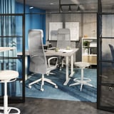 Moderne kontorlokaler med tre hvide ergonomiske kontorstole med mesh-ryg ved et bord, sat på et blåt tæppe.