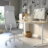 Moderne hjemmekontor med lysegrå MARKUS kontorstol, træbord, skærm, lampe og pyntegenstande.