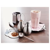 Kafferedskaber og krus i rustfrit stål med skumkunst.