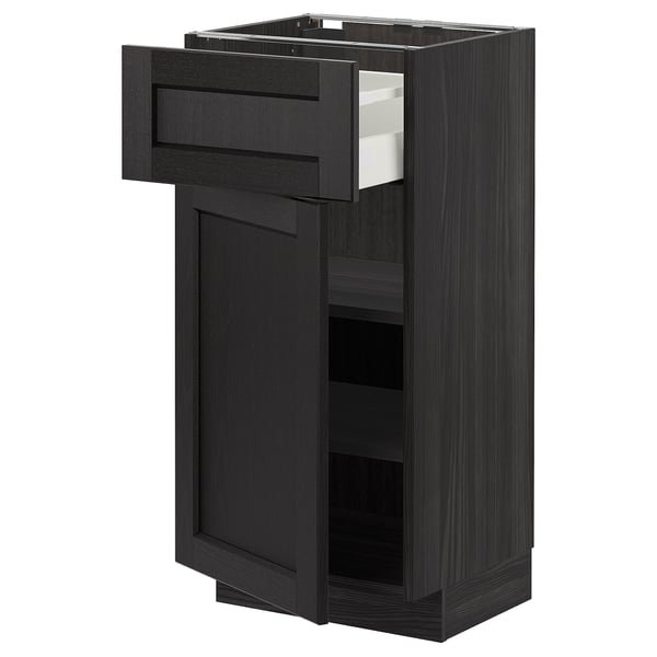Mørkt køkkenskab i træ med åben skuffe, der viser hylder. Traditionelt design med skrå kanter.