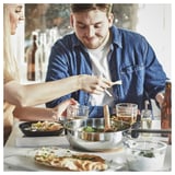 Folk laver mad i køkkenet med sauterpande.