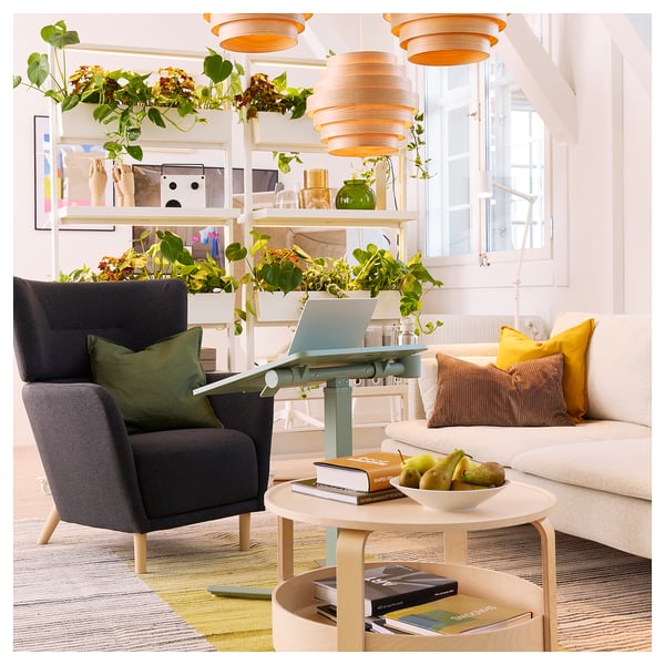 Moderne opholdsstue med grå stol, hvid sofa, laptopbord og farverig indretning.