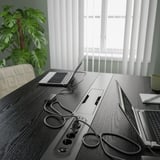 Et konferencebord sat op med bærbare computere til et møde. Bordet har et indbygget strømmodul for nem opladning. Frodig grøn plante tilføjer naturlig indretning.