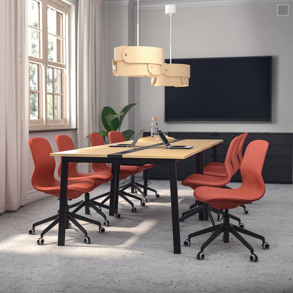 Moderne mødelokale med stort beige MITTZON-bord, orange långfjäll-stole, stilfuld pendel og storskærm, velegnet til erhvervsbrug.