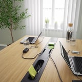 Moderne konferencebord med indbyggede strømudtag til opladning af enheder, med minimalistisk design og kabelhåndteringssystem.