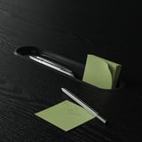 Sort skrivebordsarrangør holder kuglepenne og grønne sticky notes, en seddel lyder venligst ring til boris.