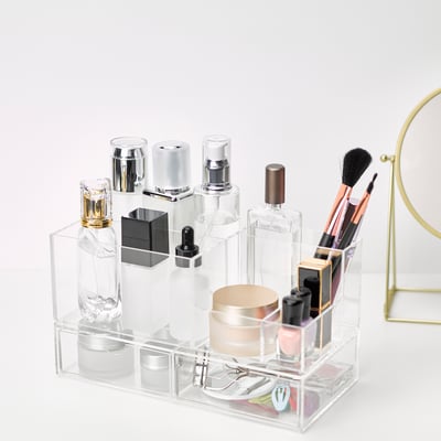 Klar akryl makeup organizer med forskellige rum til flasker, børster og tilbehør, der giver nem organisering og synlighed.