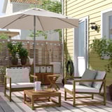 Havemøbelsæt med beige hynder, træstel og beige parasol.