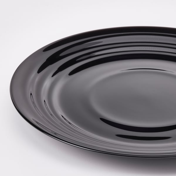 Rund, sort plade med et blankt, bølget design på en hvid overflade, der reflekterer lyset, viser håndværk af høj kvalitet og slank finish.