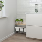 Moderne køkkenhjørne med hvid murstensvæg, åbent skab, planter, blender, opbevaringsbokse.