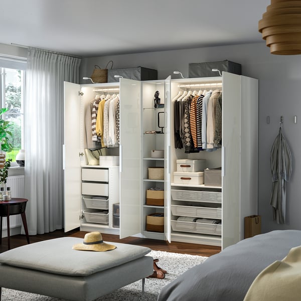Moderne garderobe med organiseret tøj og opbevaringsbokse, integreret belysning og en skammel med hat.