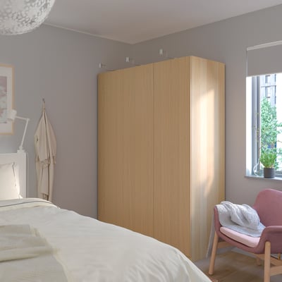 Moderne soveværelse med stort IKEA PAX garderobeskab, frakke og plante.
