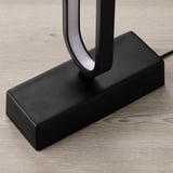 Moderne sort gulvlampe med buet led, på træ.