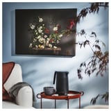 Hyggelig stue med hvid sofa, røde accenter og blå vægkunst.