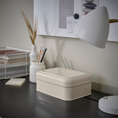 Lille hvid PLOGFÅRA kasse på et skrivebord, ved siden af en lampe og kuglepenne. Organizer passer godt sammen med andre skrivebordsartikler.
