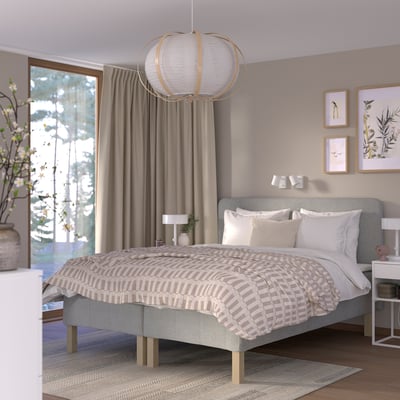 Soveværelse med beige tema med stor RÅHOLMAR seng, grå sengegavl, matchende stel, runde lys, mønstrede gardiner.