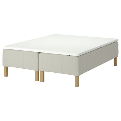 En IKEA RÅHOLMAR sengebund i hvid med træben. Den er designet med en moderne, minimalistisk stil, der giver støtte og komfort til en madras.