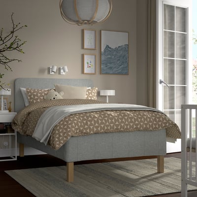Moderne soveværelse med grå RÅHOLMAR seng, mønstret beige sengetøj, gråt sengegærde, vægkunst og hvidt natbord.