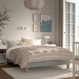 Hyggeligt soveværelse med RENFJÄLLET seng, beige-hvidt sengetøj, lille legetøj, moderne kunst, varmt tæppe.