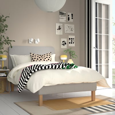 Moderne soveværelse med RENFJÄLLET seng, gråt sengetøj, abstrakt kunst, gul lampe, stort vindue, minimalistisk design.