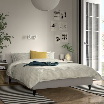 Moderne soveværelse med stor seng, minimalistisk indretning, planter og naturligt lys.