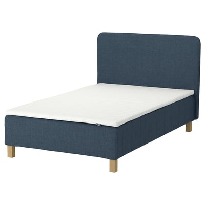 En blå IKEA RENFJÄLLET seng med hvid madras, træben og polstret sengegavl.