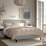 Hyggeligt soveværelse med RENFJÄLLET seng, grå sengegavl, beige sengetæppe, natborde, lamper, puder, bamse, pendel, vægkunst og plante.