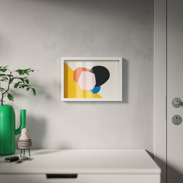 Minimalistisk ramme med abstrakt kunst. Skrivebord med plante og indretning ved siden af lukket dør.
