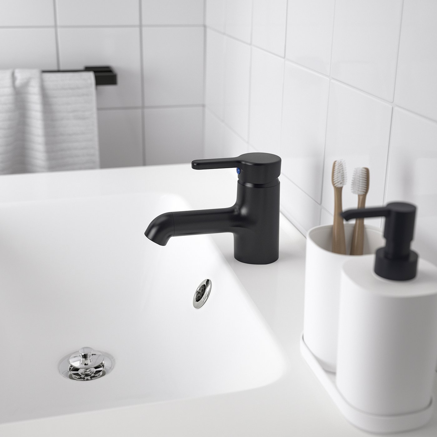 En moderne håndvask på badeværelset med et slankt sort SALJEN armatur, hvid bordplade og en tandbørsteholder.