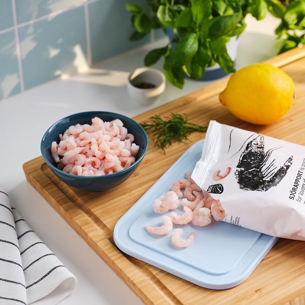 Et køkkenbord med lyserøde rejer, citron og grønt, der viser SJÖRAPPORT fisk og skaldyr.