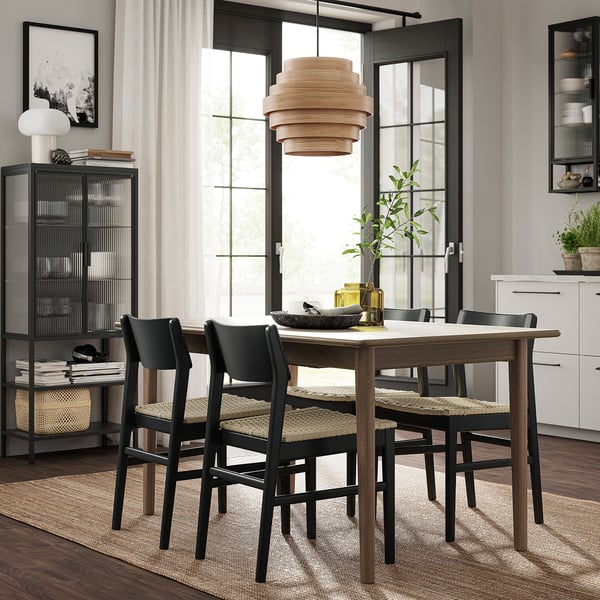 Moderne spiseplads med SKANSNÄS udtrækkeligt bord og stole, naturligt træ og sort, minimalistisk design.