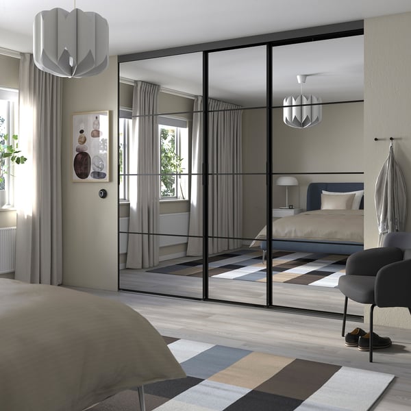 Moderne soveværelse med SKYTTA spejlskydedøre, der deler rummet, elegant grå indretning, pendellamper og blødt sengetøj.