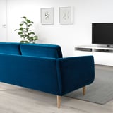 Moderne stue med blågrøn sofa, tv-stativ, plante og abstrakt kunst.