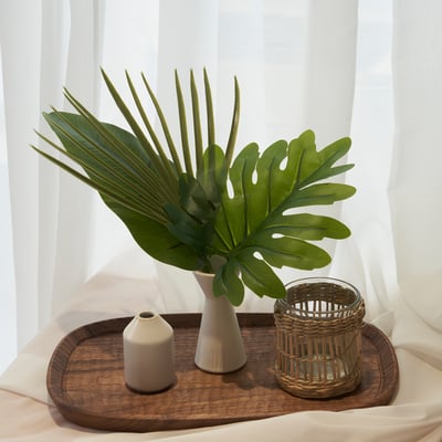 Træbakke med hvid keramikvase med grøn plante, lille beige stearinlys og vævet lysestage.