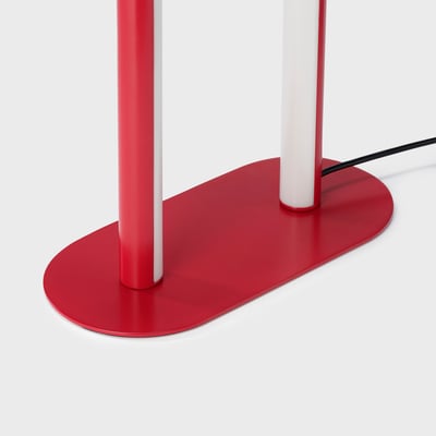 Billedet viser en rød og hvid SOLVINDEN gulvlampe. Dens slanke, minimalistiske design har en buet bue, der blander stil og funktionalitet.