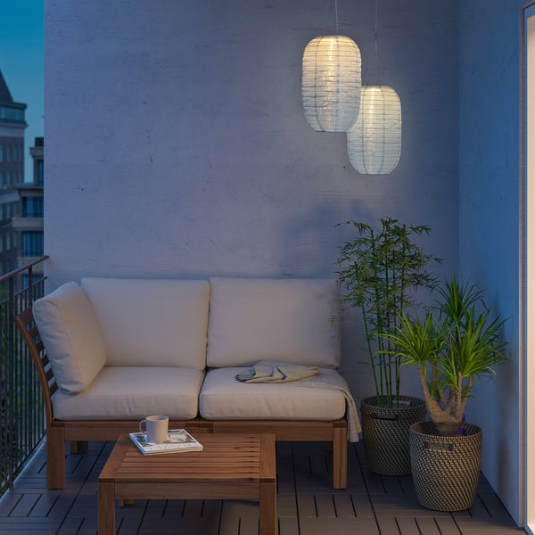 Hyggelig altan med SOLVINDEN lanterner, hvid polstret sofa, træbord og planter.