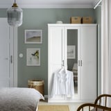 Hvid SONGESAND garderobe med spejldøre, salvievægge, fletkurve og en hængende skjorte.