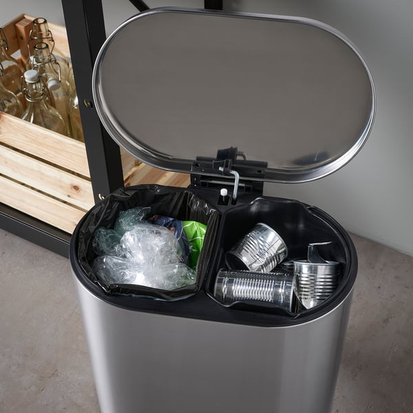 Dobbelt genbrugsbeholder i rustfrit stål, åben og viser sorteret affald: dåser og plastikposer.