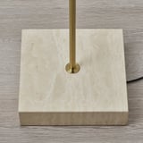 Foden på en lampe af høj kvalitet lavet af naturlig travertin med et messingfarvet stativ, der afspejler elegant håndværk.