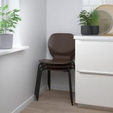 Moderne træstol nær hvidt skab med planter.