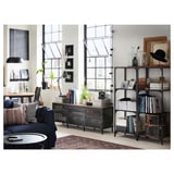 Moderne stue med blå sofa, sofabord, bogreoler og store vinduer. Dekorative genstande og planter er arrangeret rundt omkring i rummet.