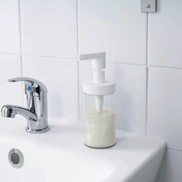 Moderne håndvask med kromarmatur og klar sæbedispenser fyldt med flydende sæbe.