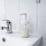 Moderne håndvask med kromarmatur og klar sæbedispenser fyldt med flydende sæbe.